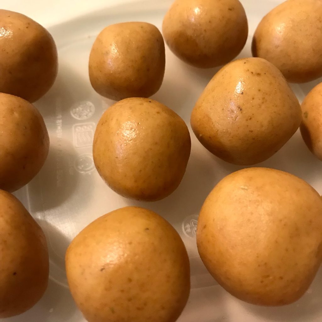 a set of homemade vegan ladoos arranged in a tupperware container.