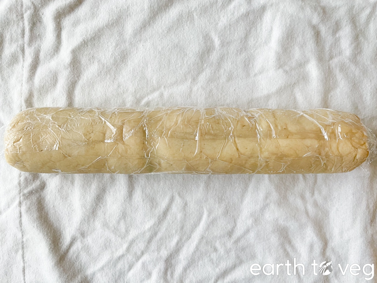 A tube of cookie dough wrapped in plastic wrap.