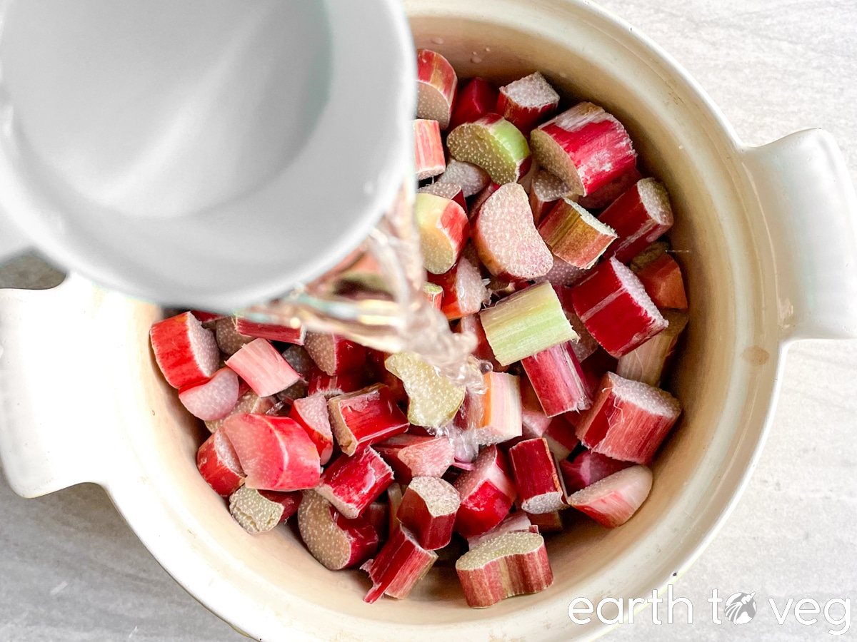 water is poured into a Dutch oven full of chopped rhubarb.