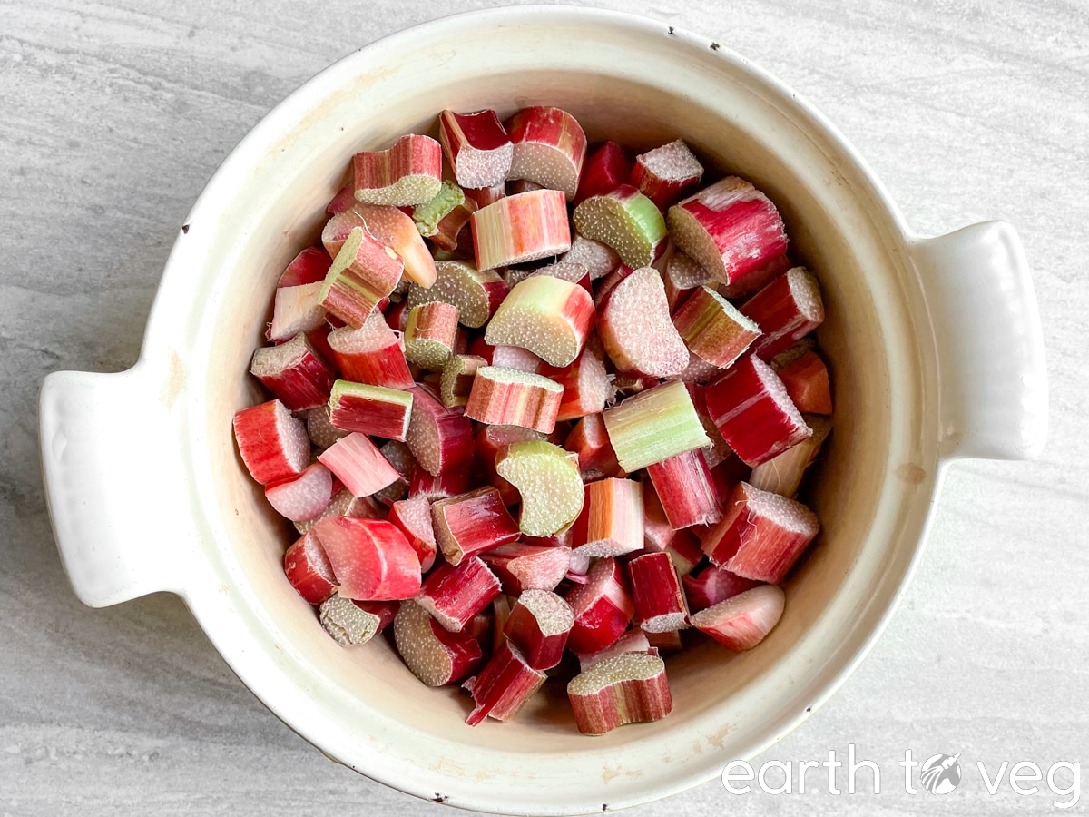 a Dutch oven filled with chopped rhubarb sits on a grey countertop.