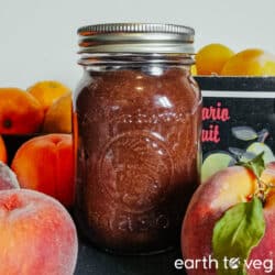 A glass pint jar of rhubarb butter next to some summer stonefruit.