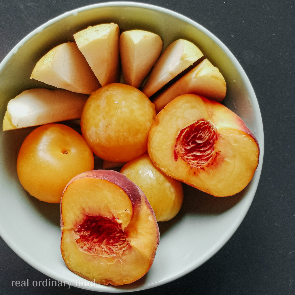 fruit bowl of pears, yellow plums, and yellow peaches