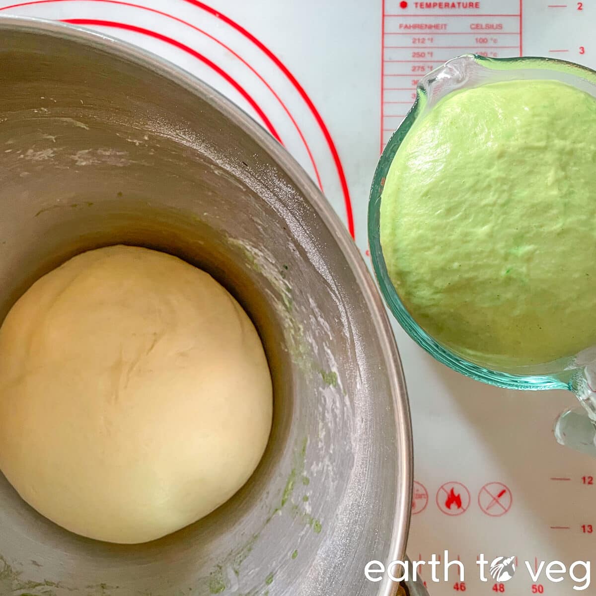 Green and white doughs sit side by side in bowls on a baking mat.