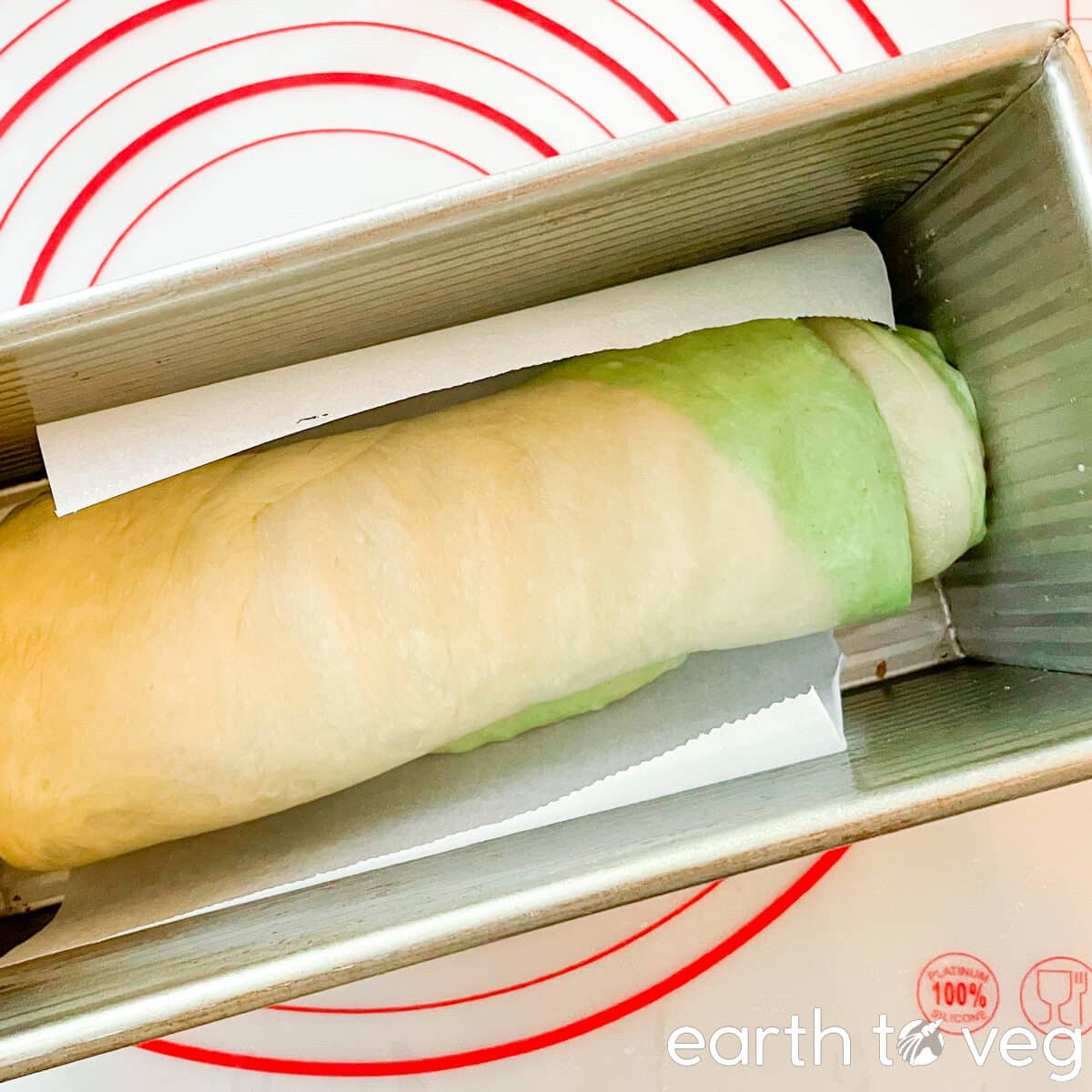 The pandan bread is rising in a Pullman loaf pan.