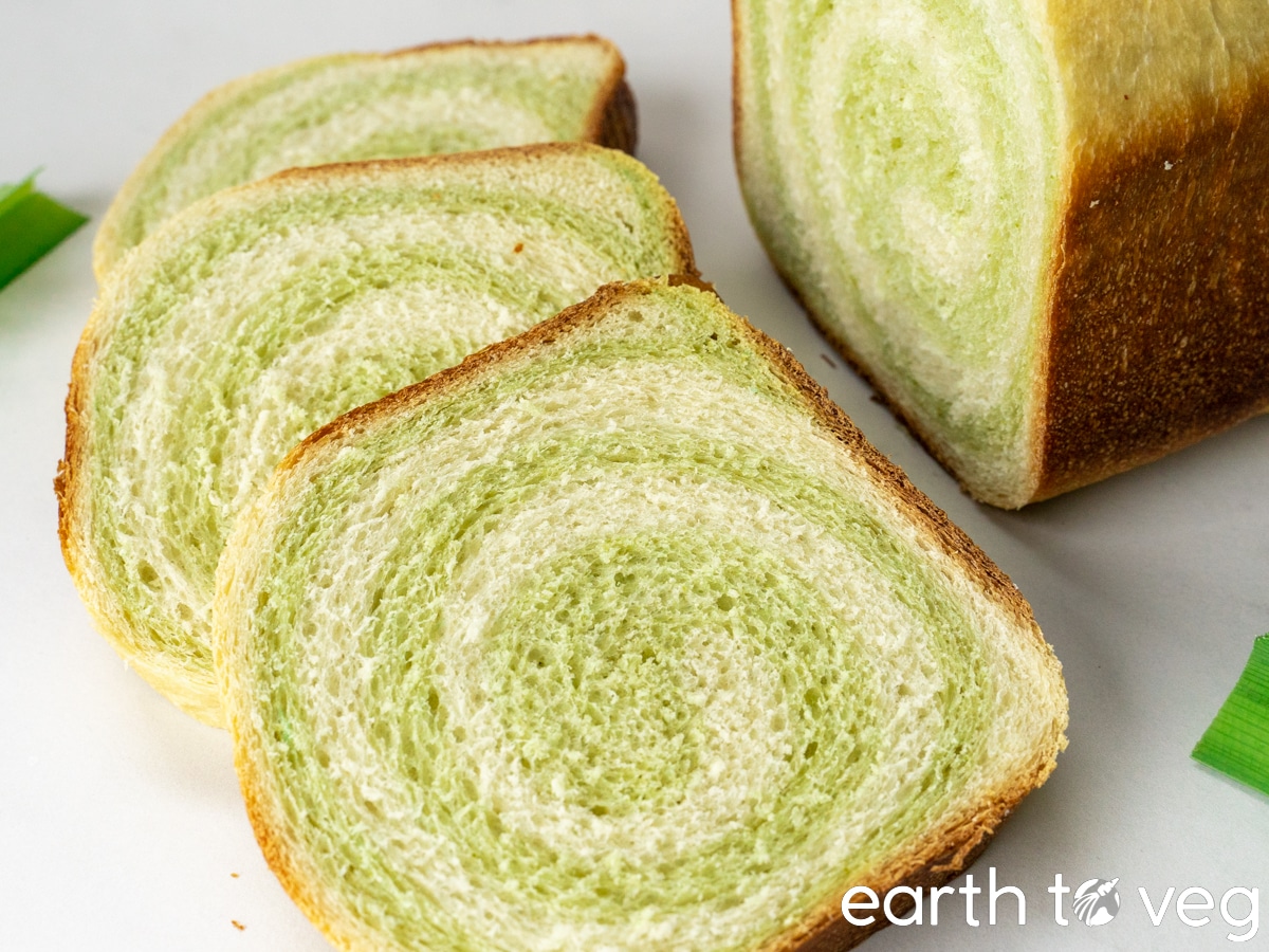 Three slices of vegan pandan bread are laid out on a white countertop.