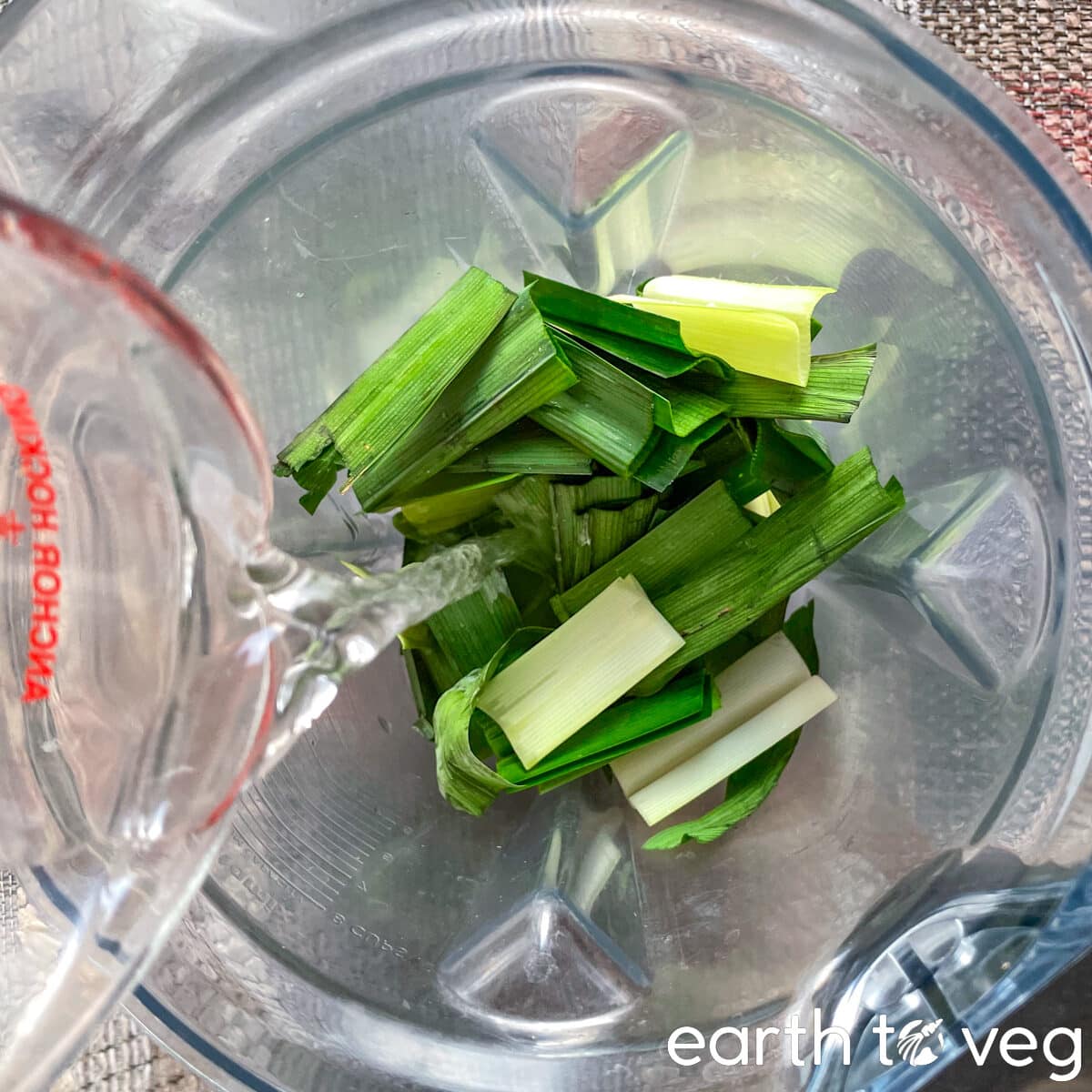 Water is poured over pandan leaves in a Vitamix blender.
