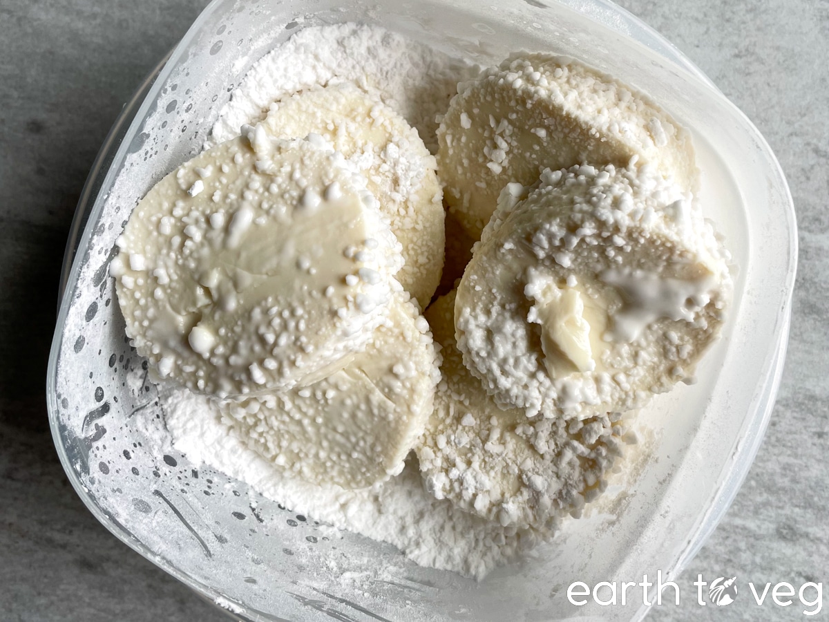 A small lunchbox filled with soft tofu slices and covered in cornstarch.