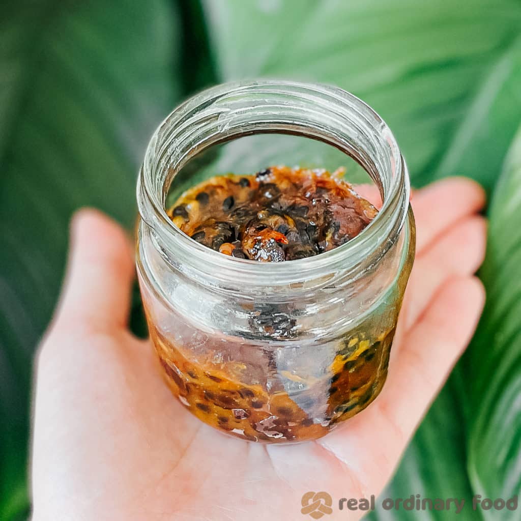 holding a small glass jar of passion fruit butter