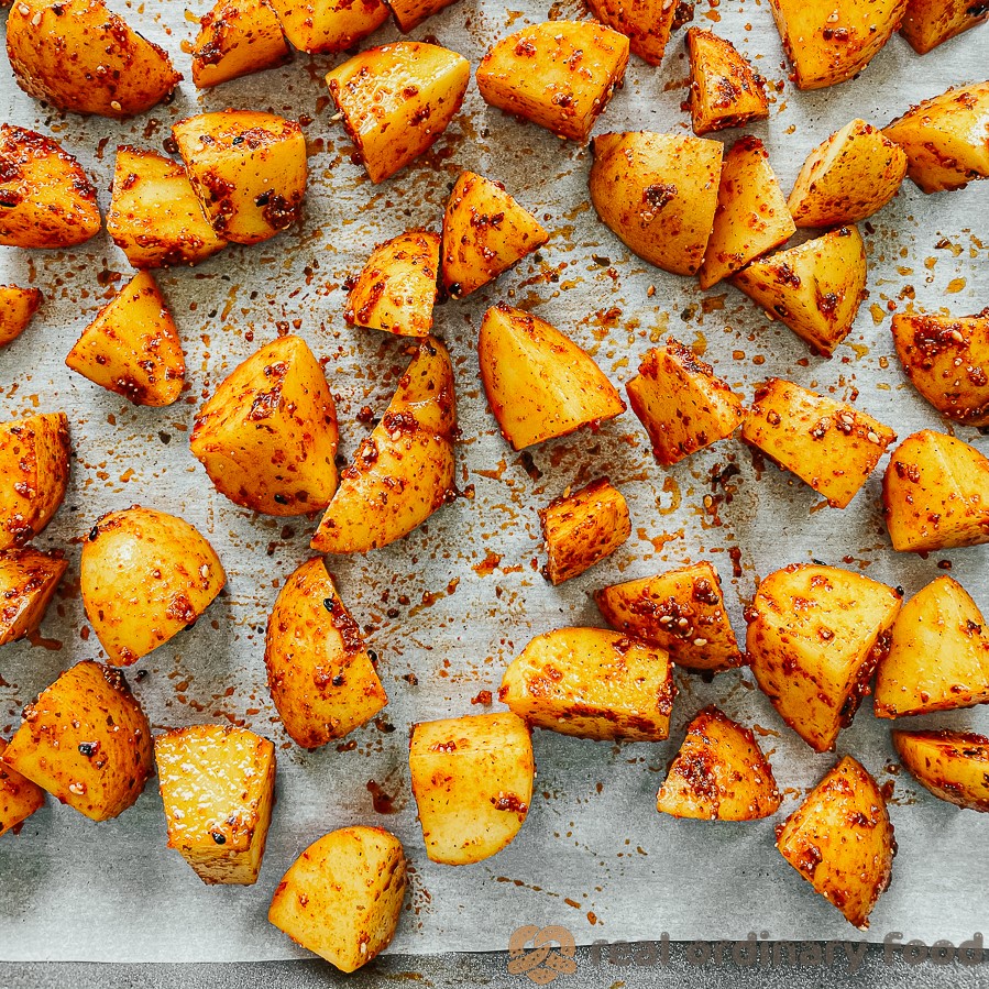 Shichimi-coated potato pieces on a parchment baking sheet.