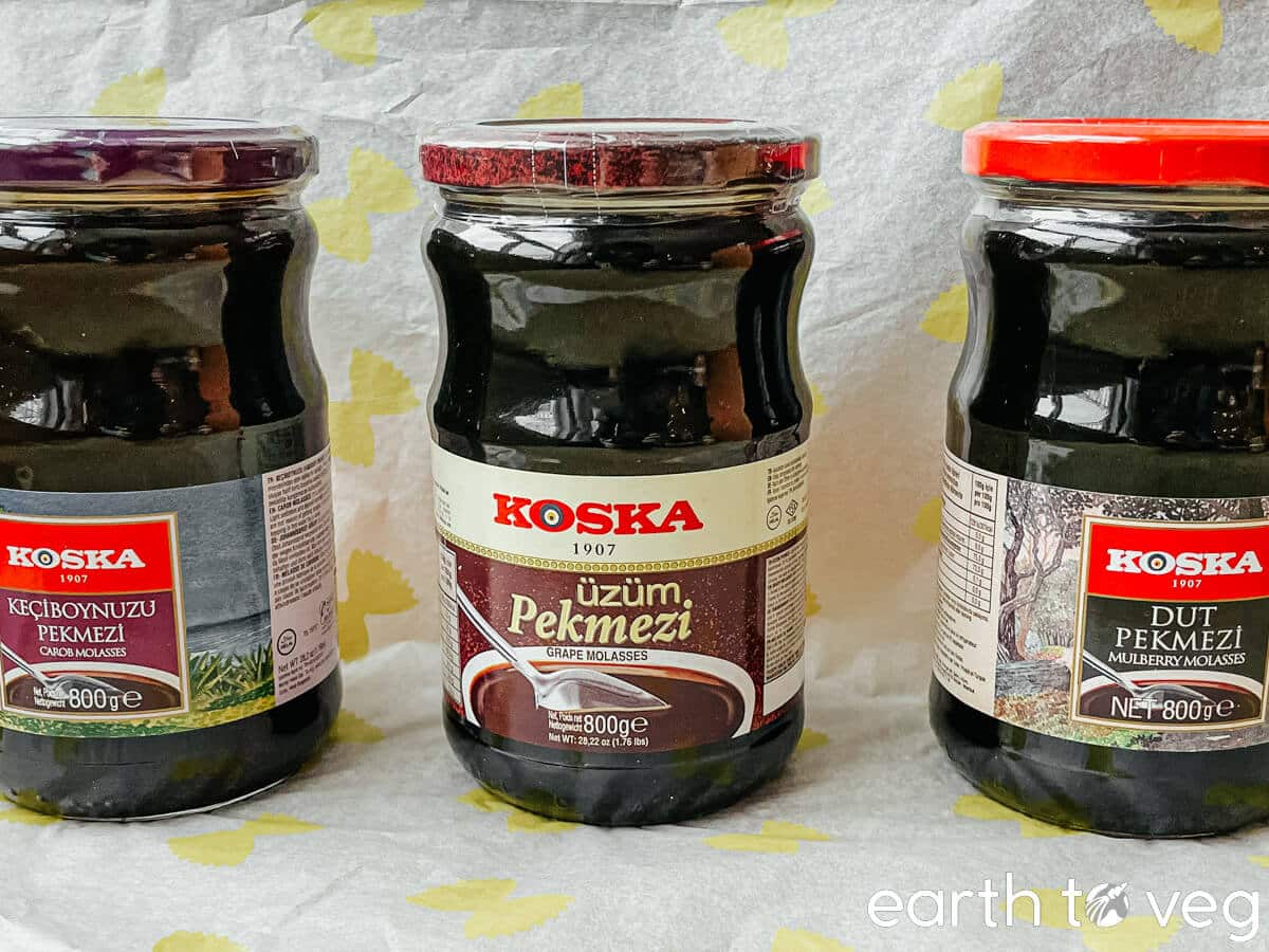 Three bottles of different Turkish pekmez varieties: grape, carob, and mulberry.