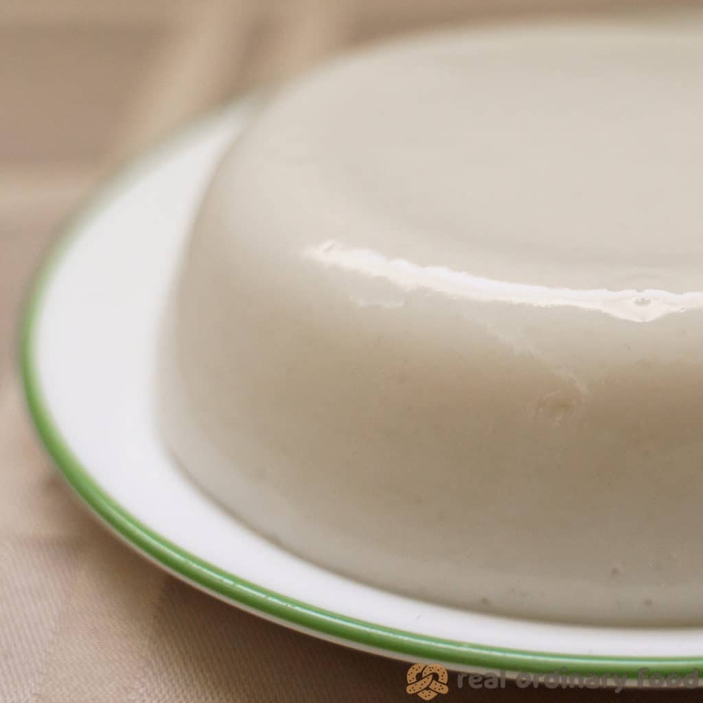A freshly unmolded muhallebi rice pudding on a plate with green trim.