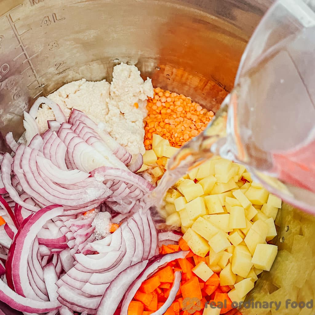 Water is poured from a plastic measuring cup into the Instant Pot.