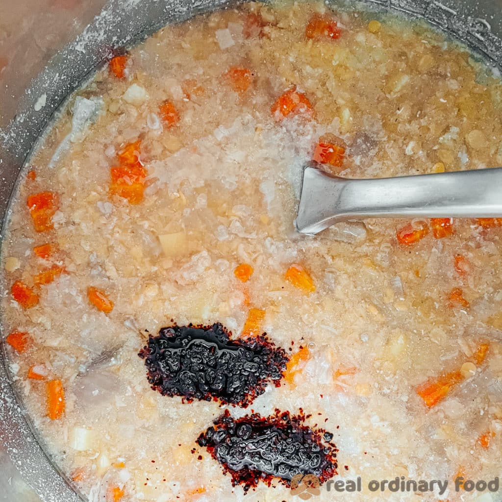 Stirring in the aleppo pepper and lemon juice into the soup.