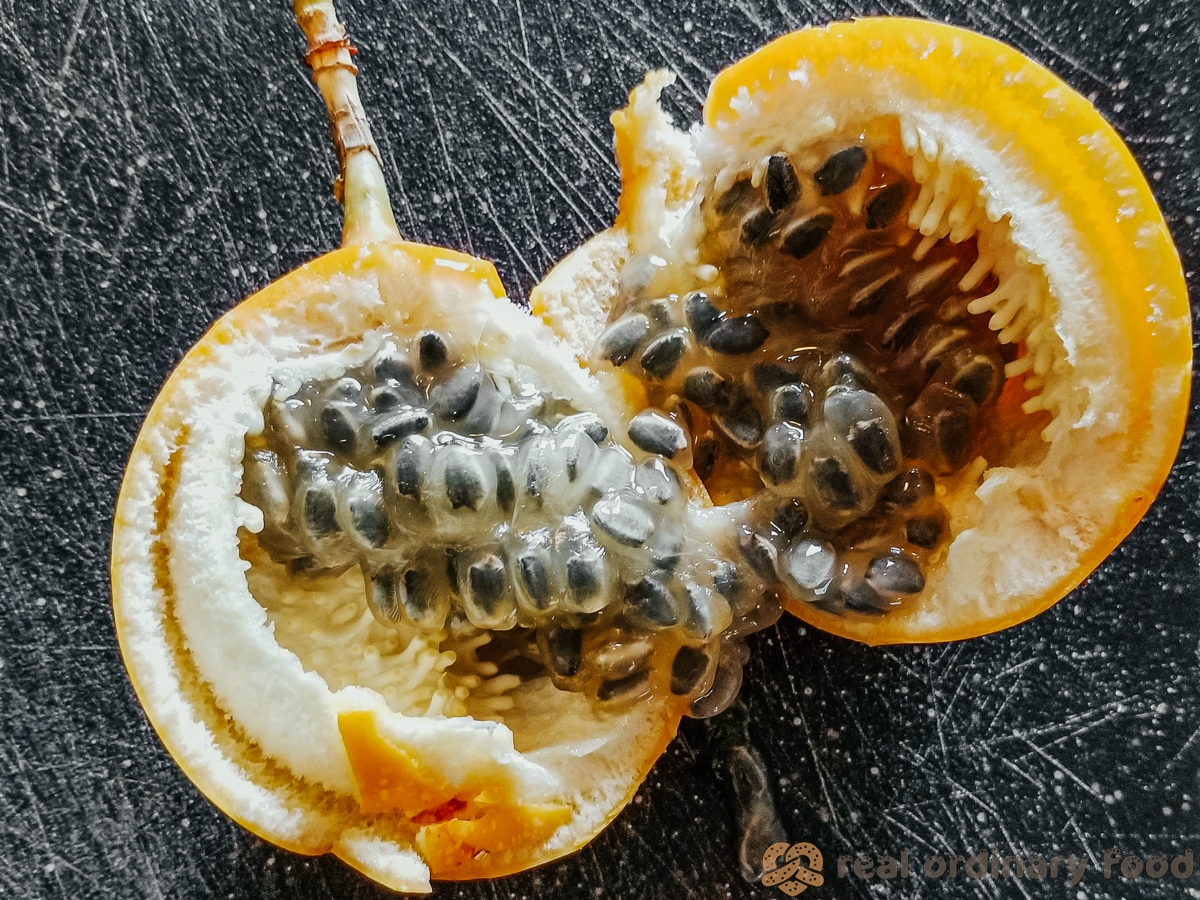fresh passion fruit cracked open on black cutting board