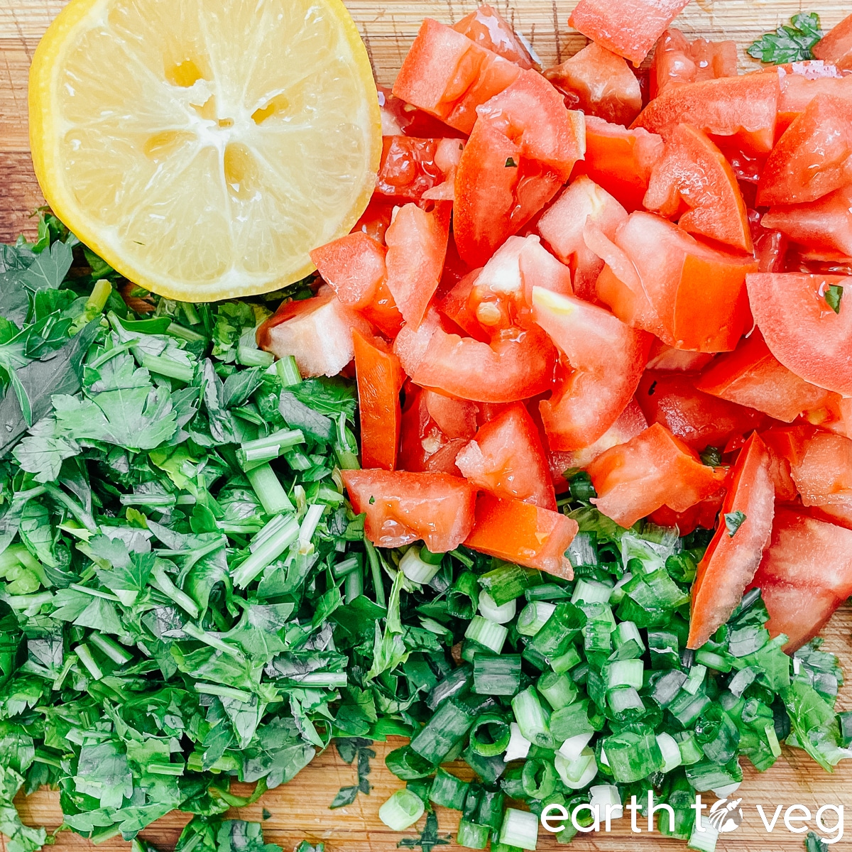 Chopped fresh vegetable ingredients for kısır salad on a wooden chopping board.
