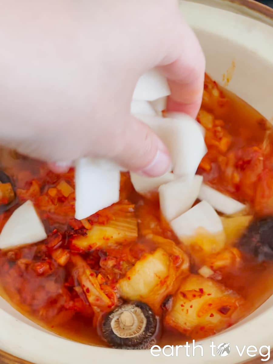 Slices of chopped radish are added to the soondubu broth.