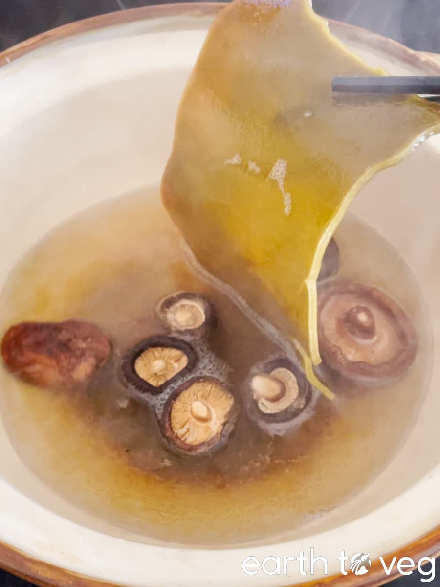 The boiled kelp (kombu) is removed from the yuksu broth with a pair of chopsticks.