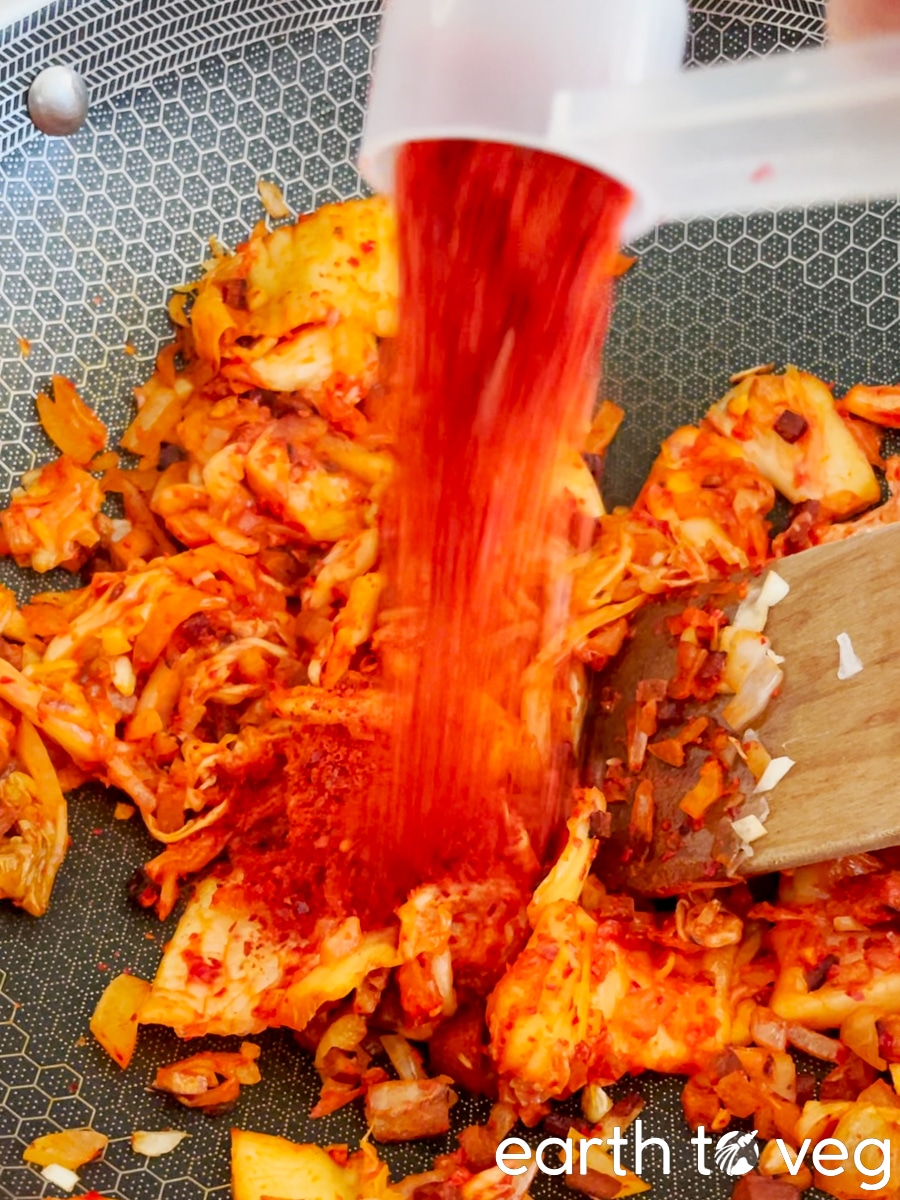 A spoonful of gochugaru is added to the kimchi.