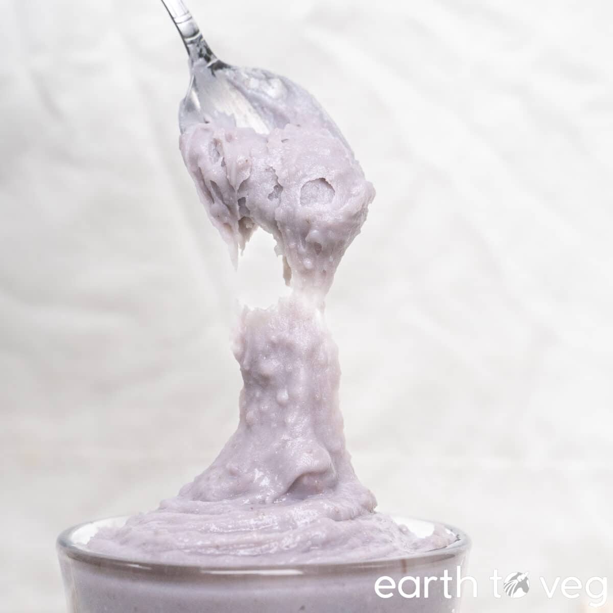 A thick spoonful of taro paste is held up to the camera.