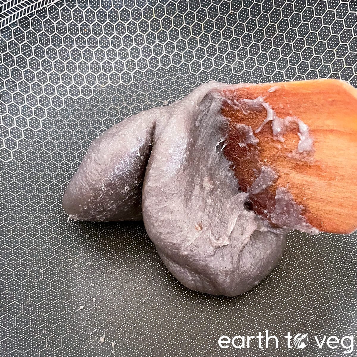 The thickened taro paste begins to lift off the wok surface and stick to the wooden spatula.