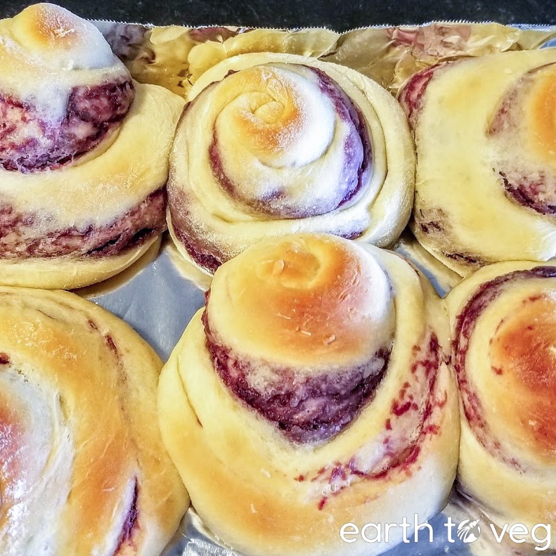 Six thick ube ensaymada buns on an aluminum baking sheet.