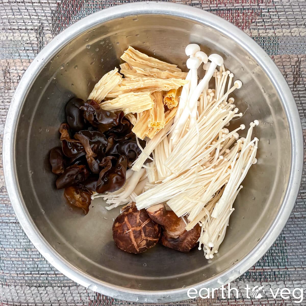 Mushrooms, fuzhu (beancurd sticks), and wood ear fungus in a stainless steel bowl.
