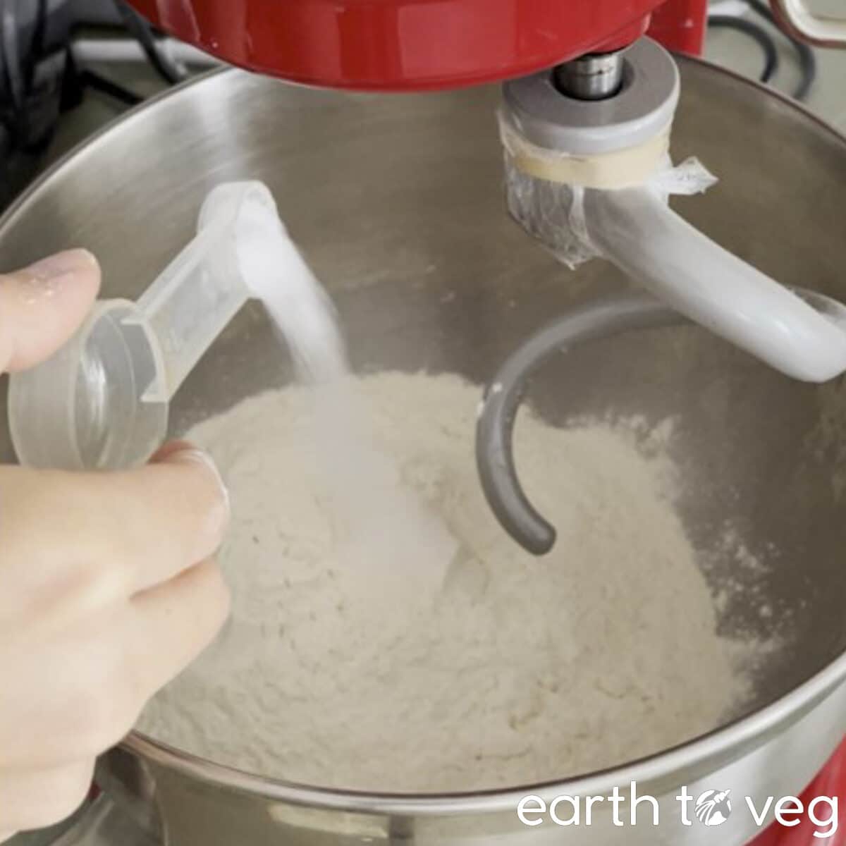 A spoonful of salt is poured into a bowl of flour.