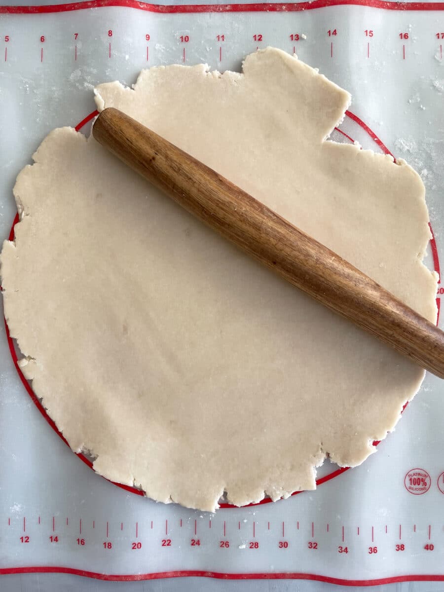 Rolling out and trimming an unbaked pie crust.