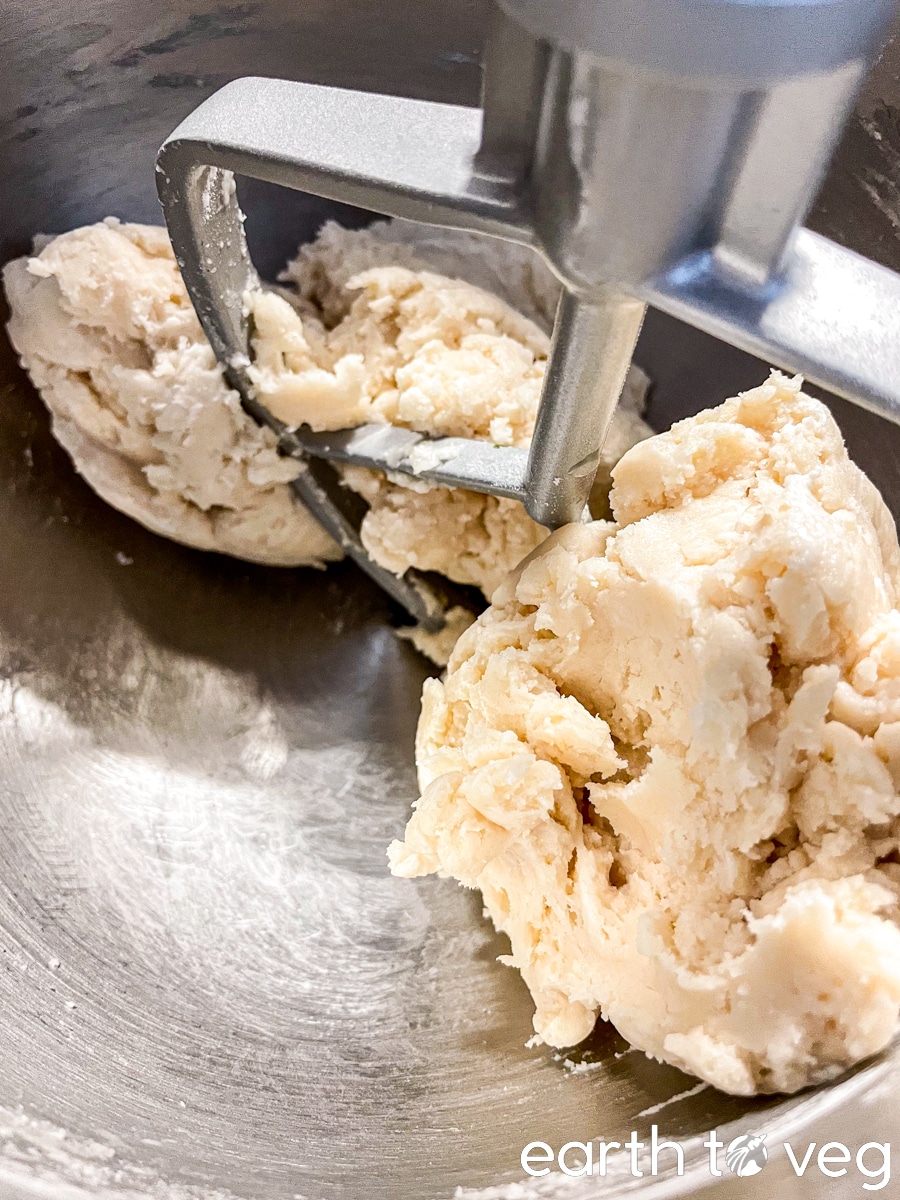 The pie dough forms one clump as it continues to be mixed.