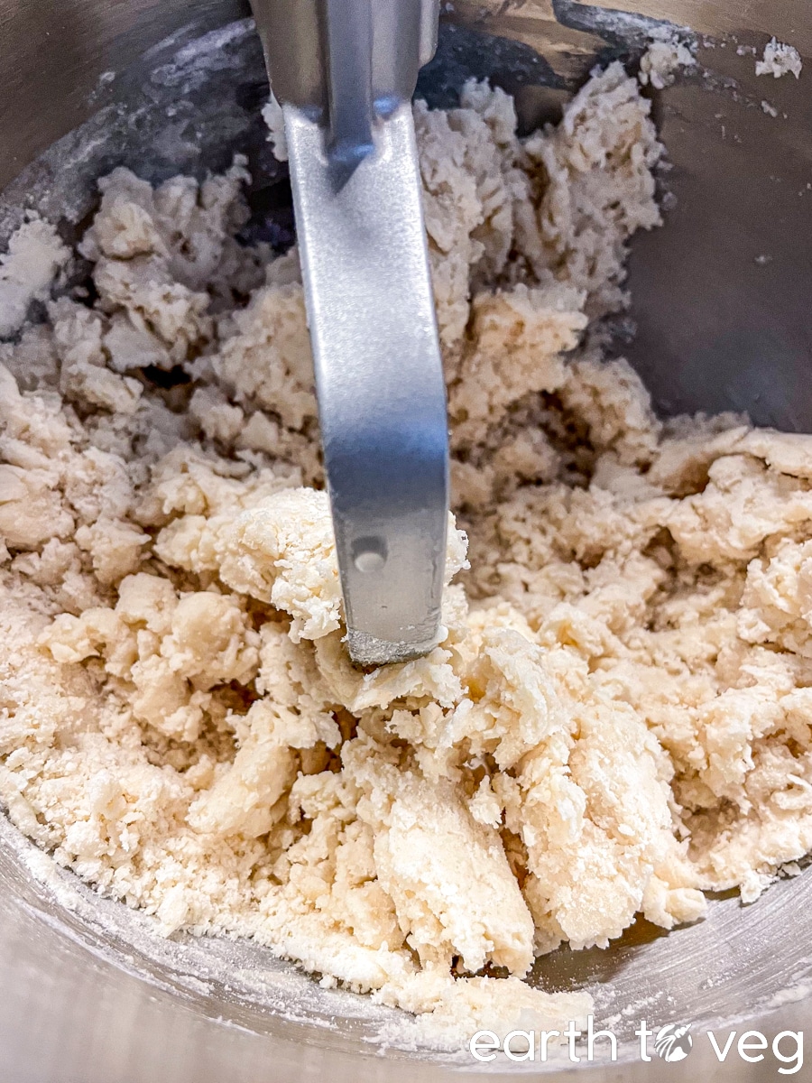Pie crust dough is coming together after sprinkling over with cold water.