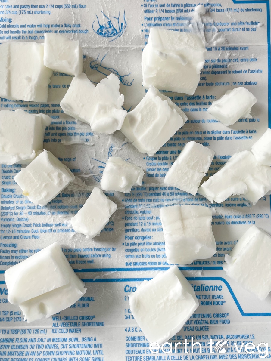 Scattered cubes of cut crisco shortening pieces on a piece of paper packaging.