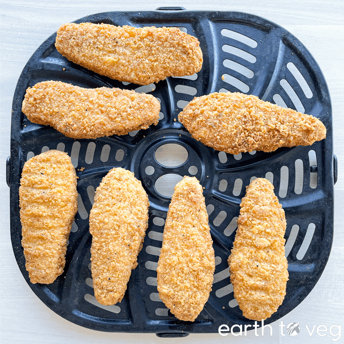 Beyond Chicken Tenders on a black non-stick air fryer tray, before and after air frying.