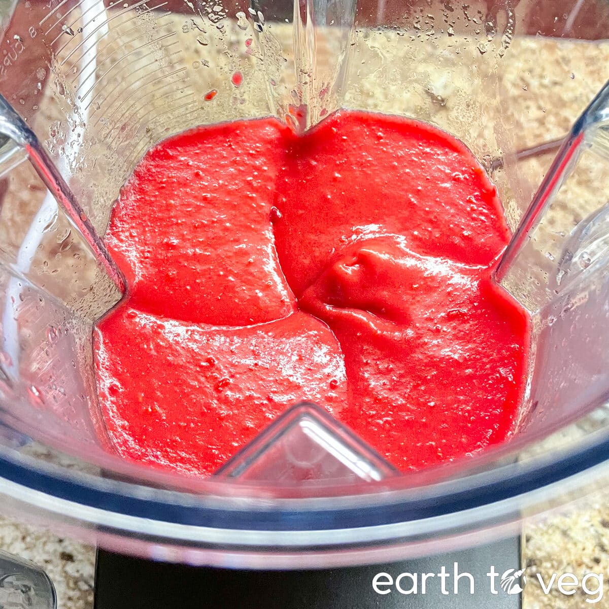 Bright red freshly blended hawthorn berry puree in a Vitamix blender.