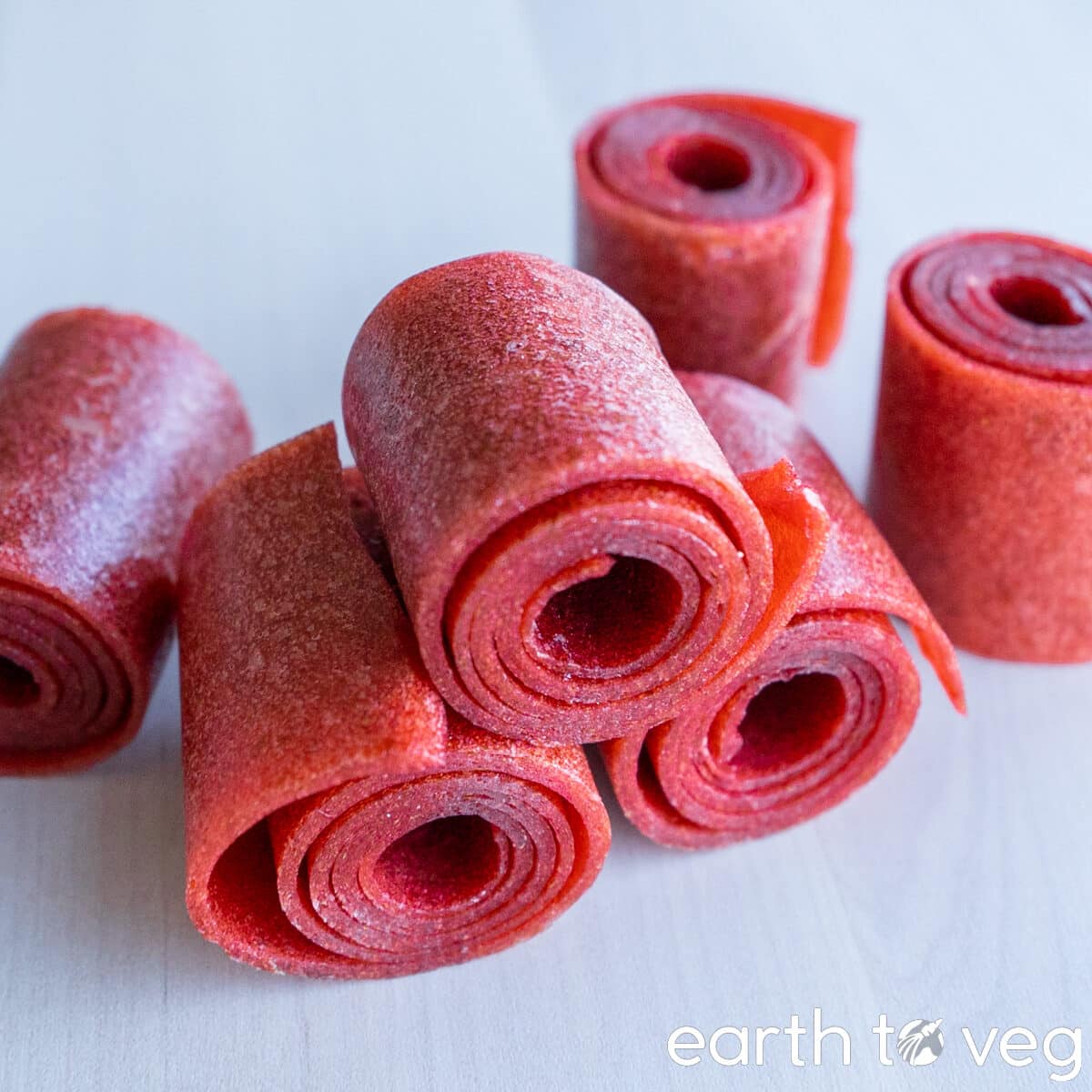 Three stacked sliced rolls of hawberry leather in the foreground with more in the back.