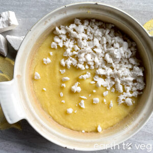 Dutch oven filled with mamaliga cornmeal porridge with cheese scattered over top