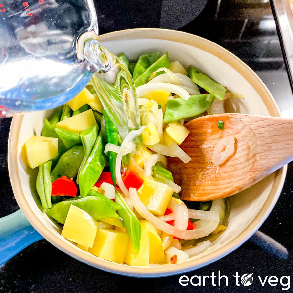 Water being poured into a pot full of vegetables.