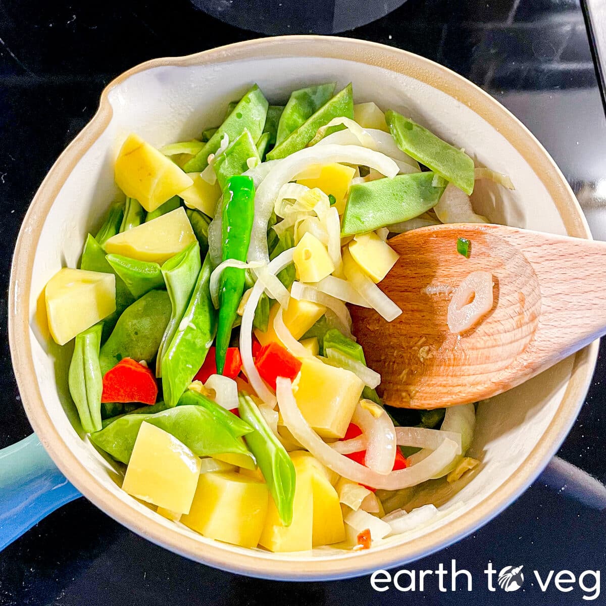 Assorted vegetables stirred together in a stockpot.