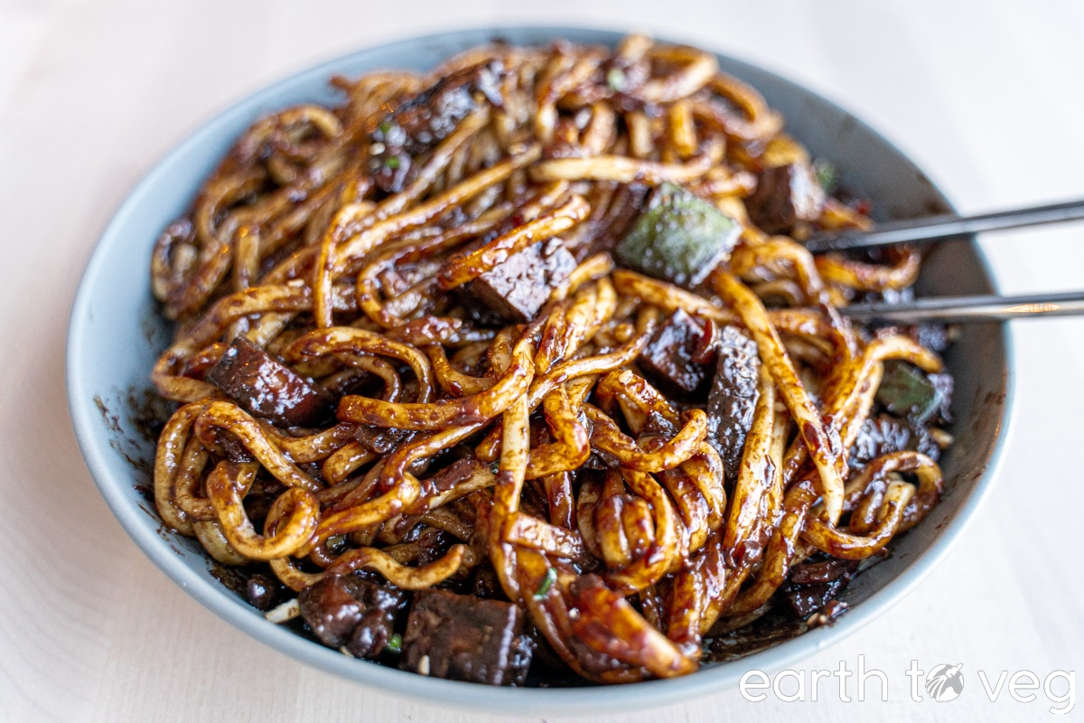 jajang sauce mixed with noodles in a large pasta bowl with chopsticks