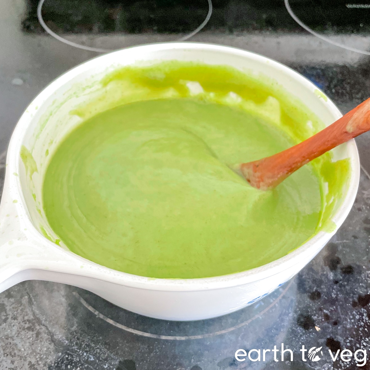 A spatula continuously stirs the pot of pandan kaya mixture as it slowly thickens.