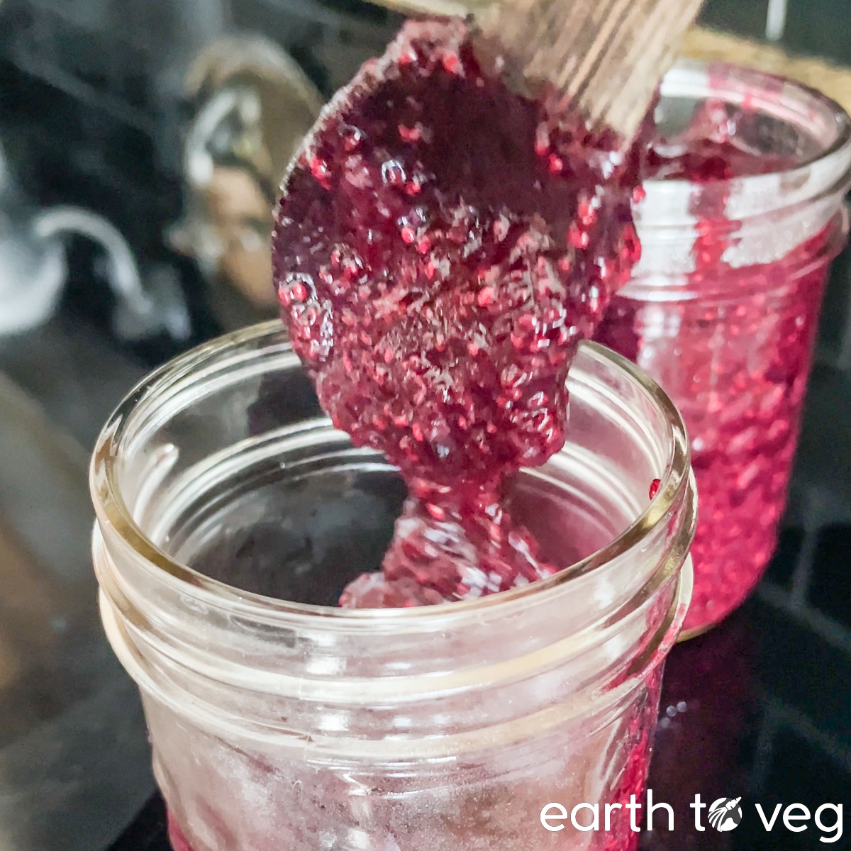 Blueberry chia jam is spooned into small glass jars.