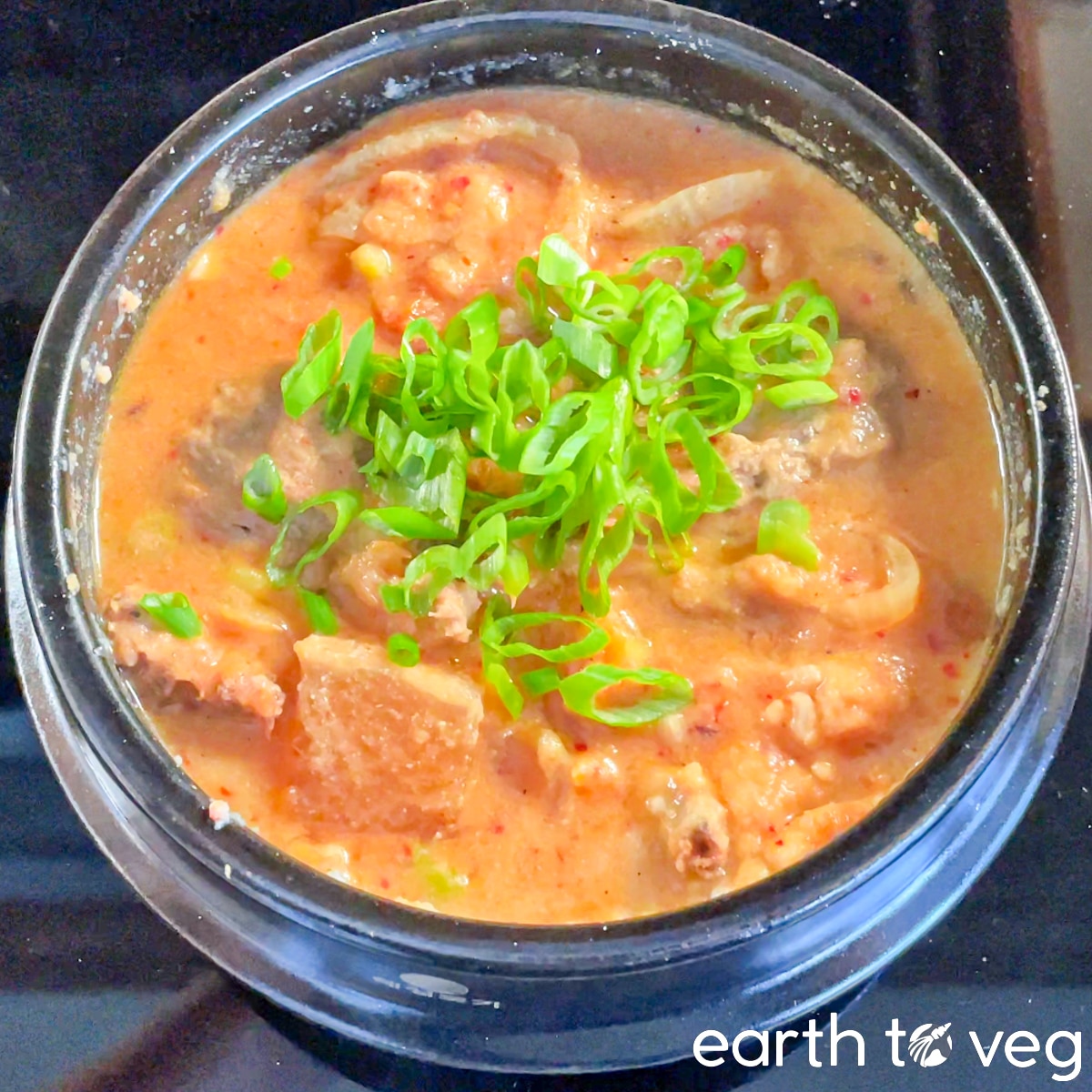 Scallions are scattered over a bubbling pot of kongbiji jjigae.