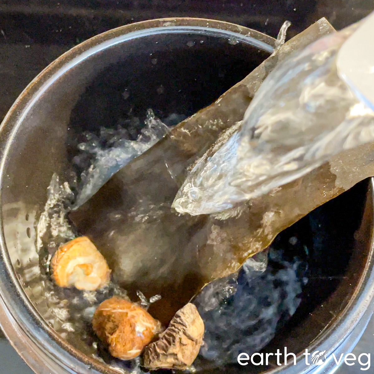Filtered water is poured over dried shiitake mushrooms and kombu in a ttukbaegi.