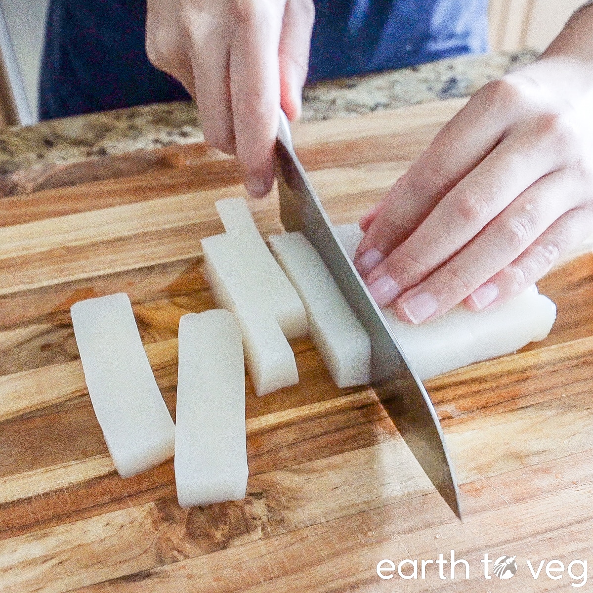 Konjac block is sliced into 1/2-inch pieces on a wooden cutting board.