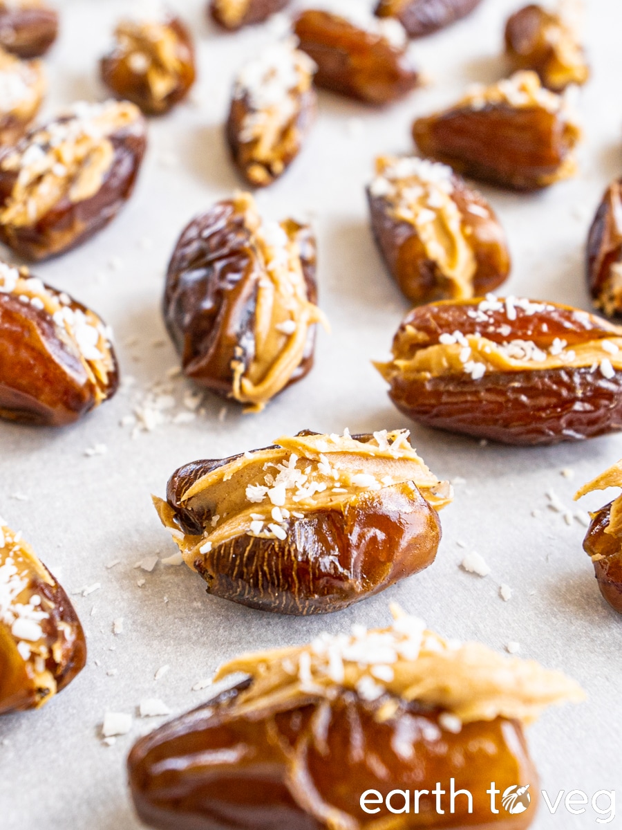 Peanut butter stuffed dates scattered on a sheet of parchment paper.
