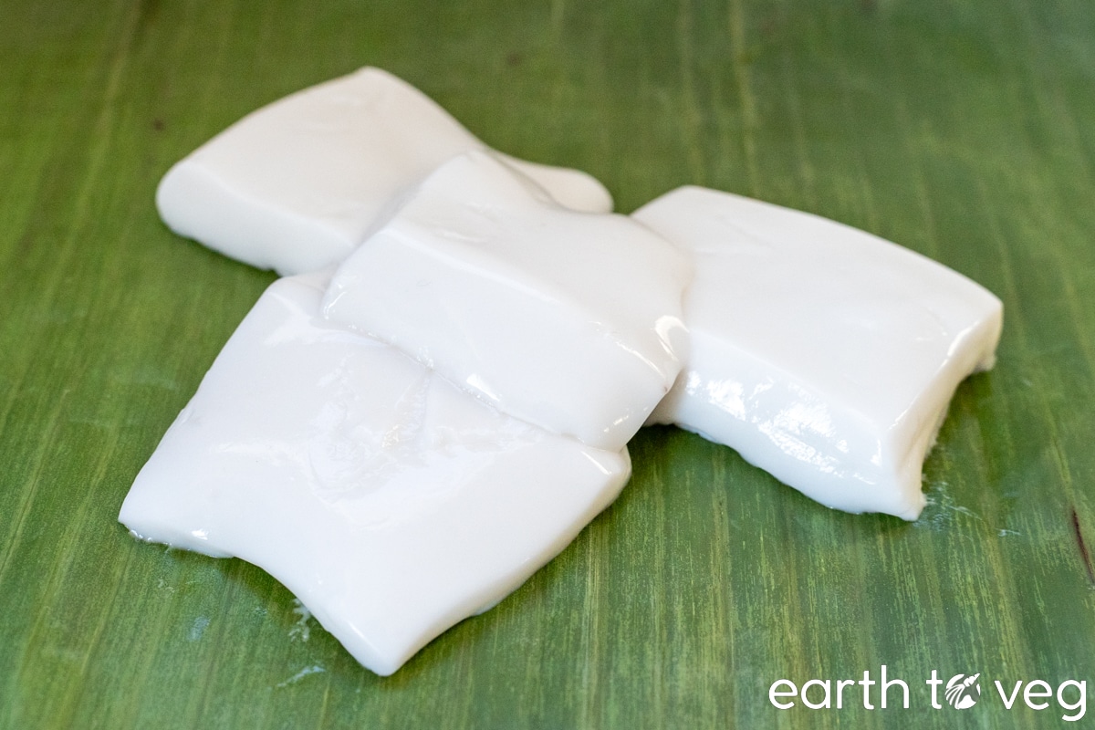 A pile of haupia squares made with tapioca starch on a large banana leaf.