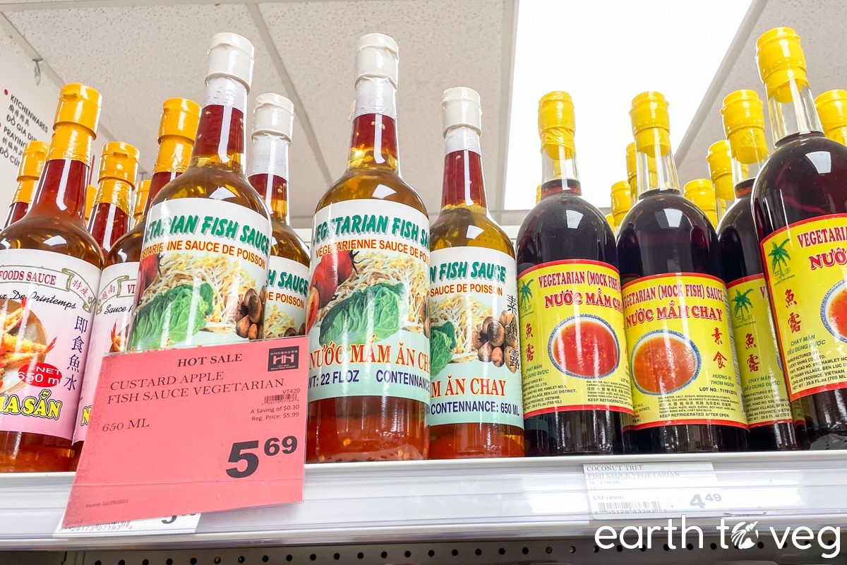Bottles of vegetarian fish sauce selling for $5.69 sit on the top shelf in a Vietnamese supermarket aisle.