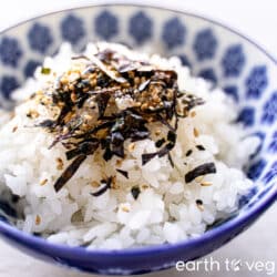 A small blue china bowl of white rice is topped with furikake seasoning.