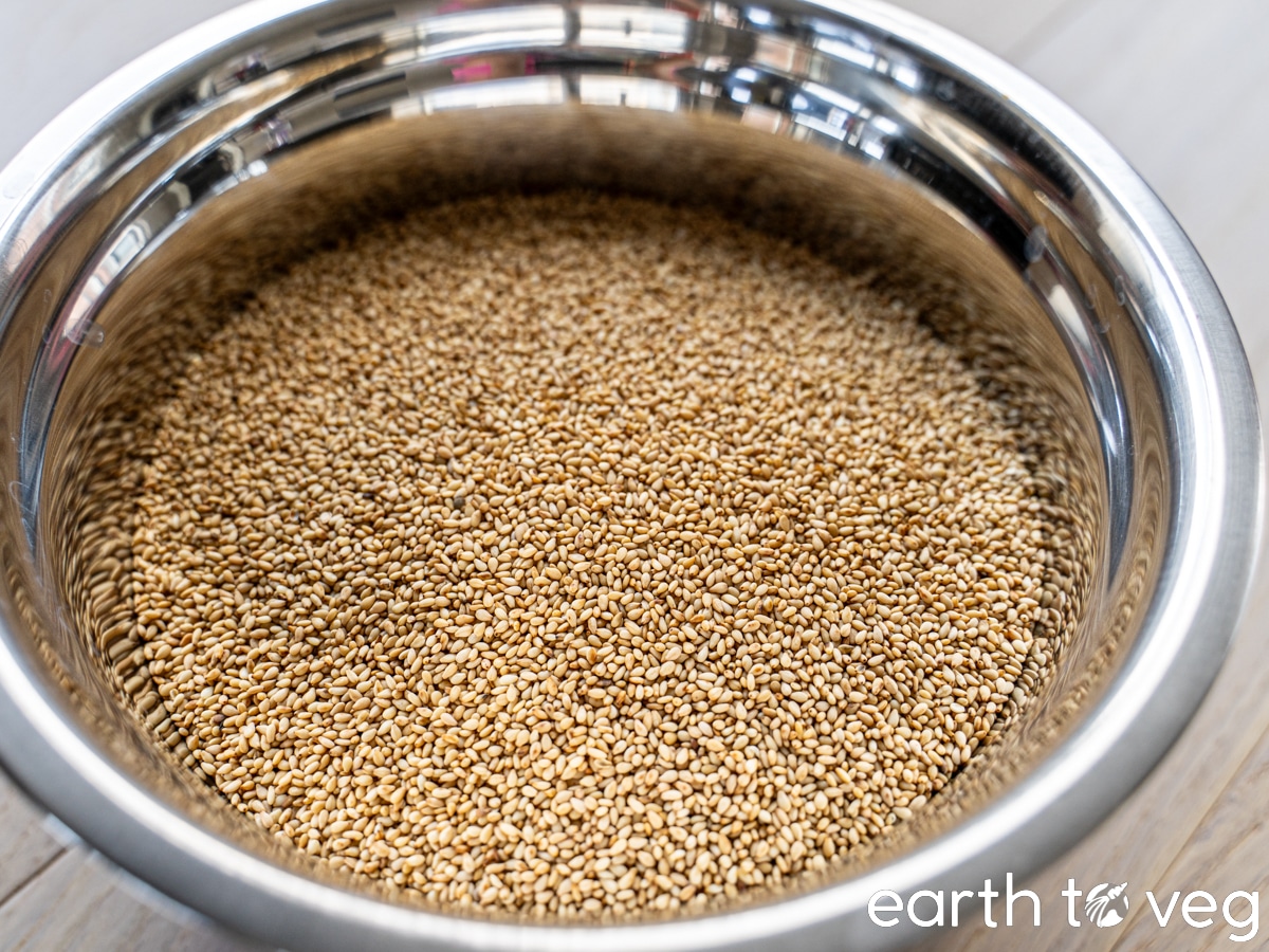 A stainless steel bowl filled with toasted sesame seeds.
