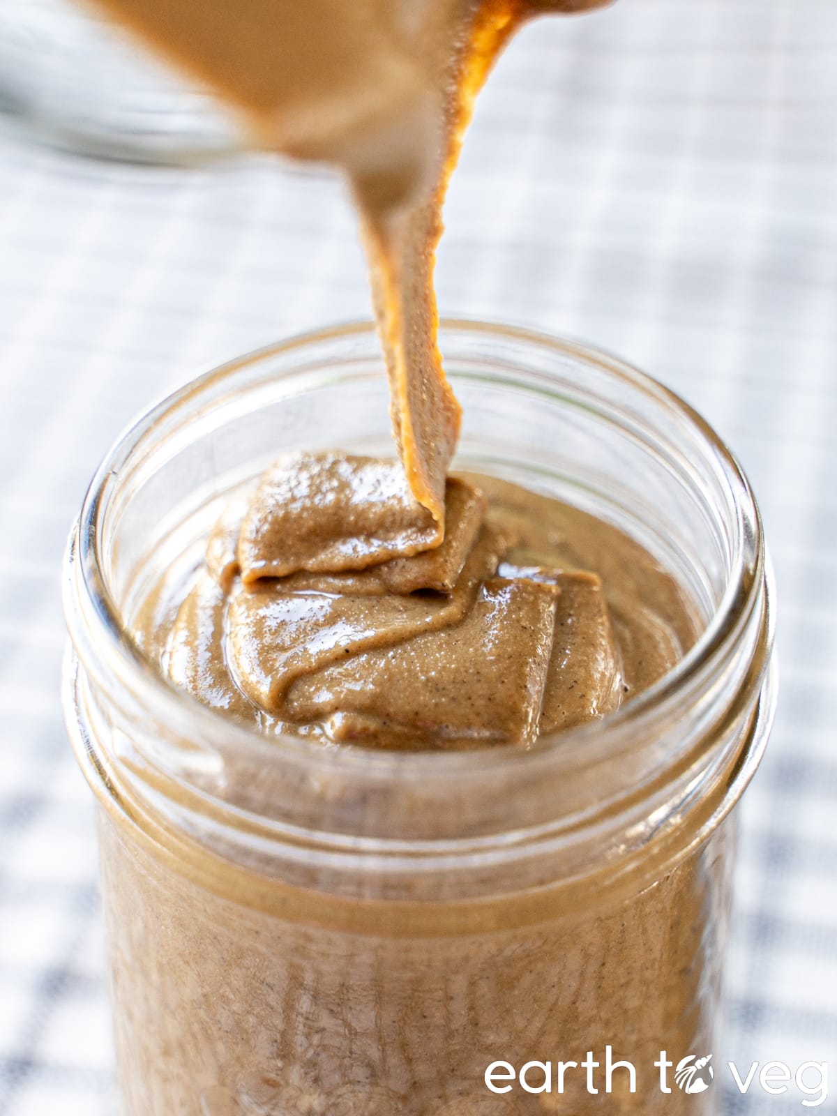 Roasted sesame butter is drizzled into a glass mason jar.