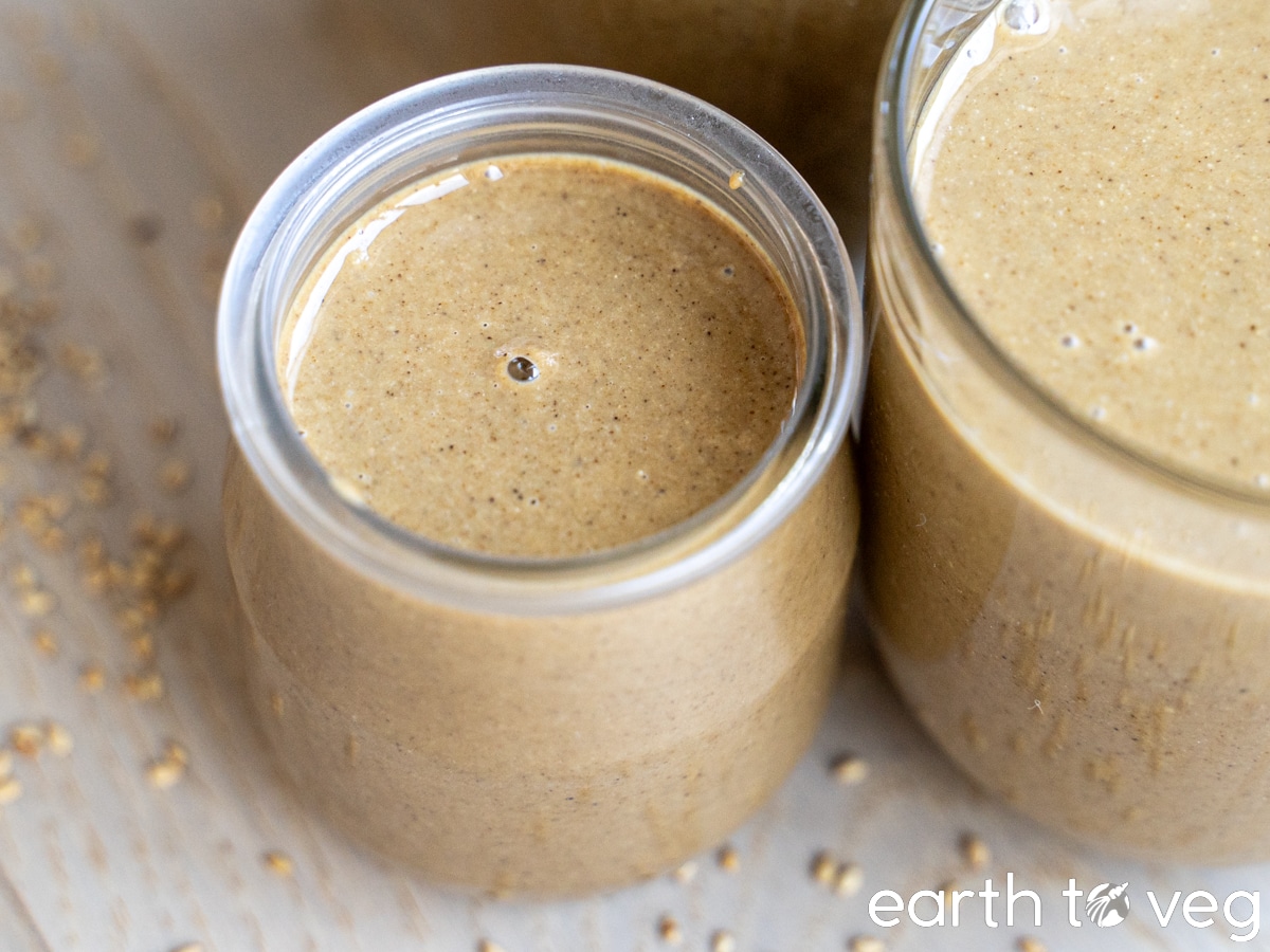 Glass jars of roasted sesame paste on a wooden table.